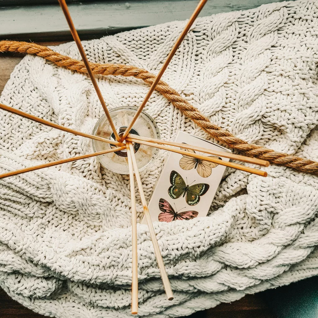Aromatic diffuser and butterflies atop a cozy knitted blanket creating a warm atmosphere.